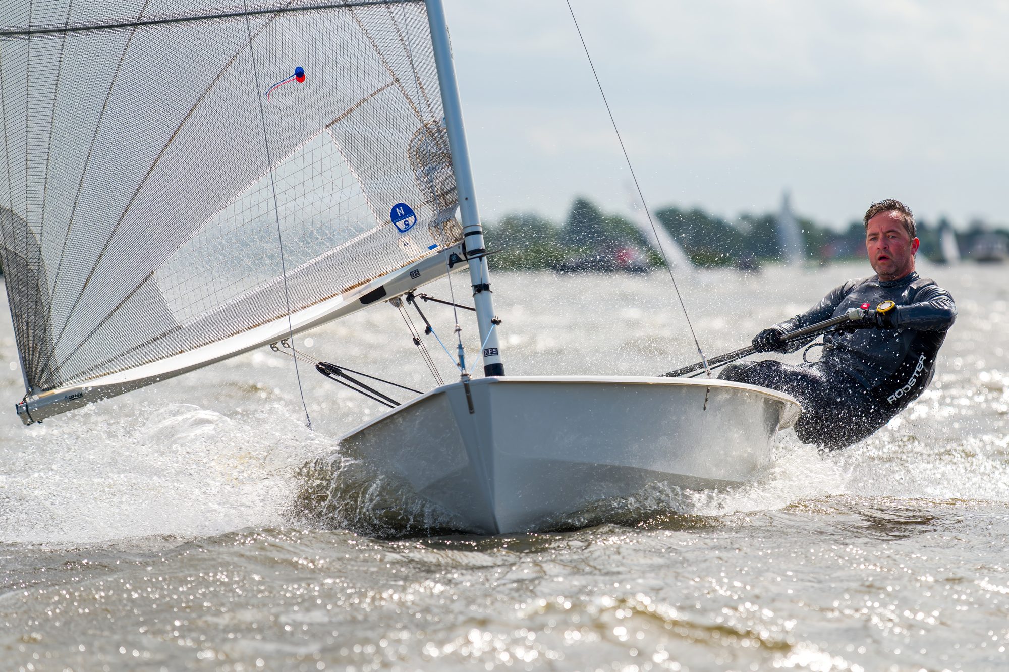 Solozeiler plant met veel vaart en opspattend water over het Veluwemeer